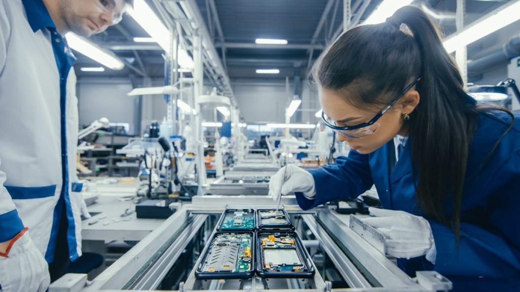 A worker in an electronics factory assembles a component.