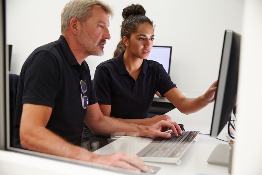 Two staff members review a file in a product data management system.