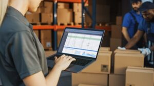 A woman in a warehouse looking at a laptop 