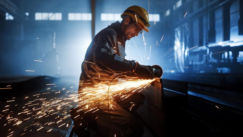 A manufacturing worker cutting metal