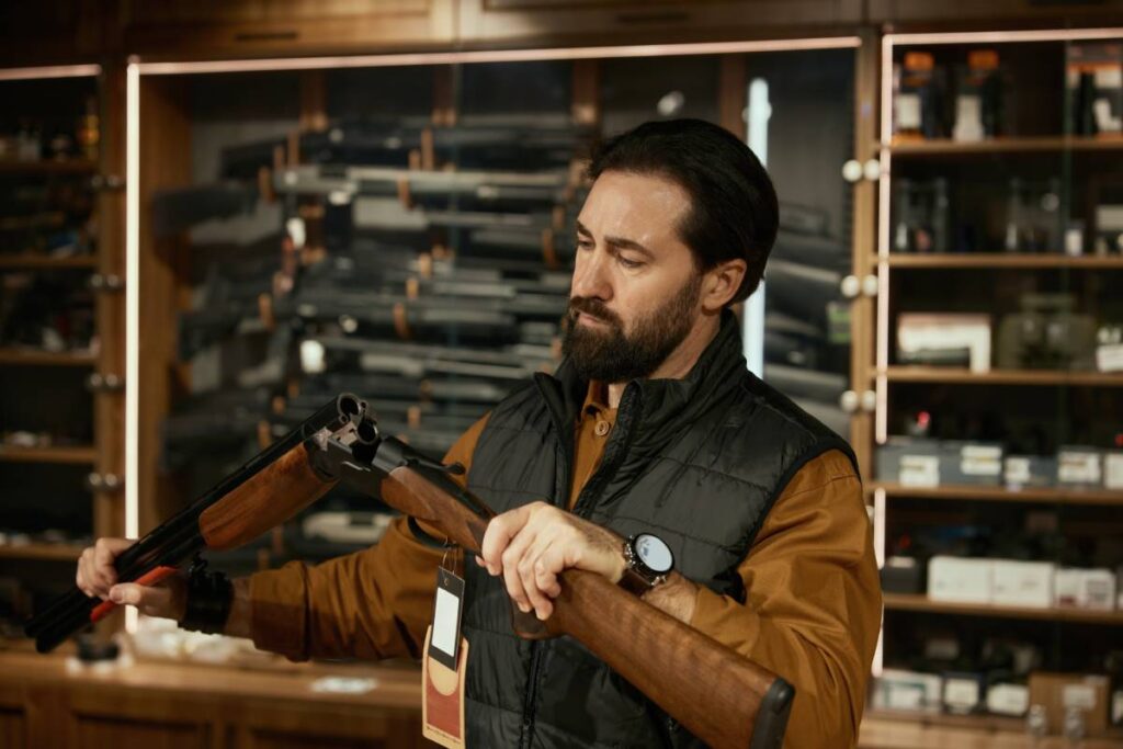 A man in a gun store looking at a shotgun.