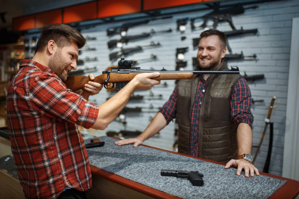 A man looking at a rifle in a gun store.