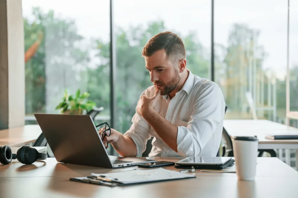 A businessman looking at a laptop at his desk.