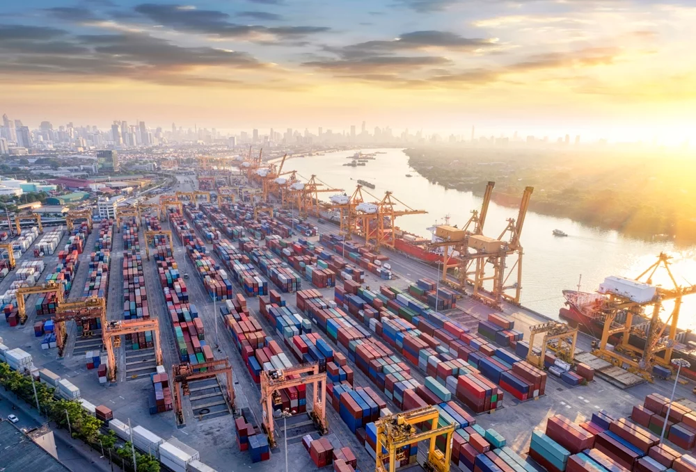 An aerial view of a large port with cranes and shipping containers.