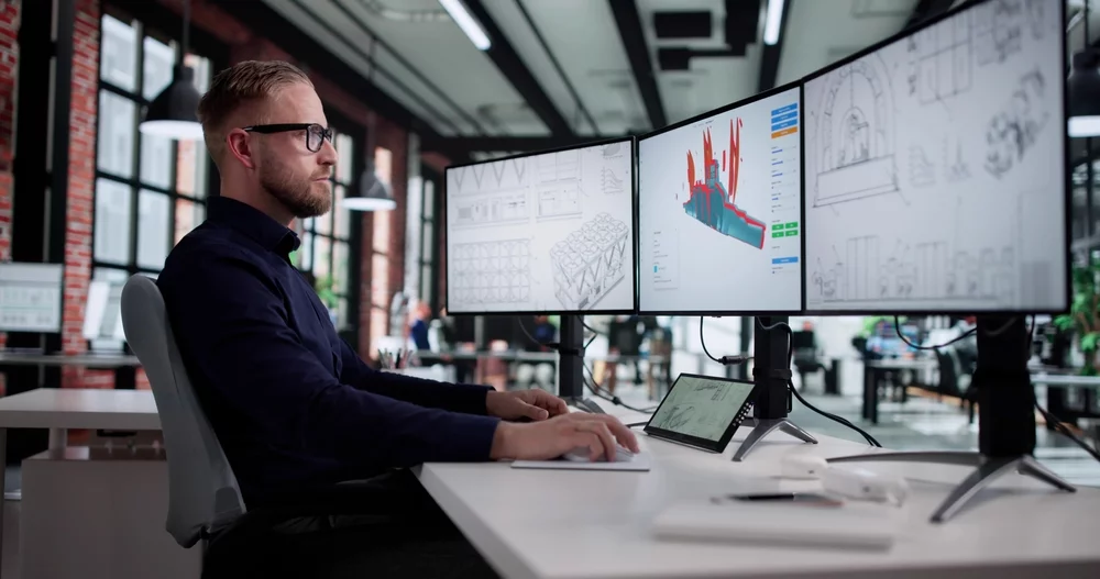An engineer working on a three-monitor computer setup.